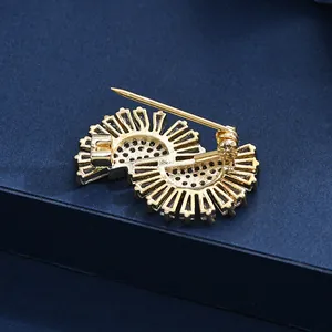 Elegant gold S-shaped brooch with pearls and zircons on a dark blue textured surface