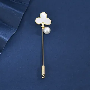 Detail of clover brooch featuring white mother of pearl and a dangling pearl pendant