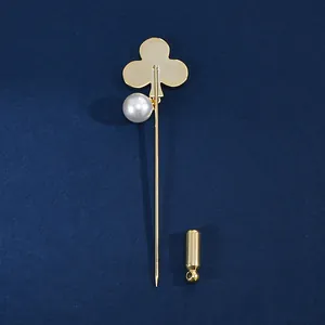 Golden clover brooch with shell pearl accent and needle cap on dark blue background