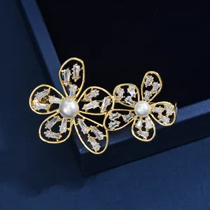 Détail macro d'une broche double fleur avec zircons et perles sur boîte en velours