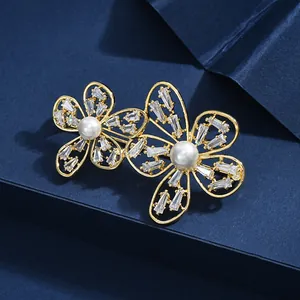 Broche fleur dorée élégante avec perles et zircons sur une boîte de luxe bleu foncé
