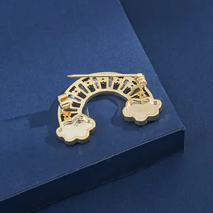 Broche nuage arc-en-ciel vue arrière avec base dorée et épingle de sûreté sur fond bleu