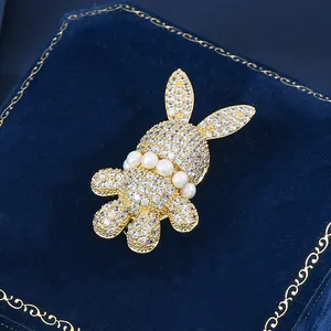 Dettaglio della spilla a coniglio con cristalli bianchi e perle su velluto blu scuro