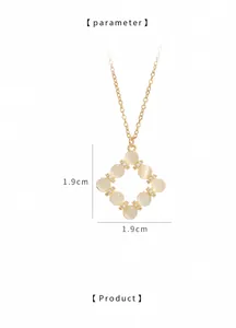 Detailed view of gold necklace with cat-eye stone pendant and hollow rhombus design