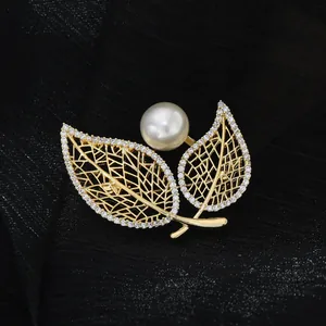 Detail of leaf-shaped brooch with gold plating, sparkling zircons and a large white pearl