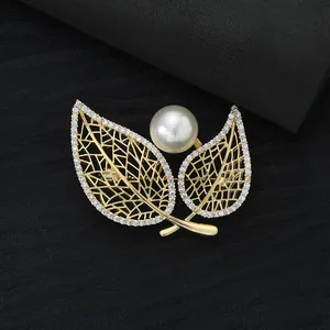 Elegant gold leaf brooch with micro-pave zircons and a large pearl on black leather