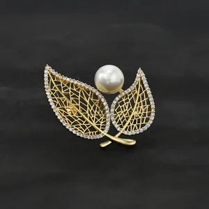 Macro view of gold-plated double leaf brooch with white pearl and micro-inlaid zircons