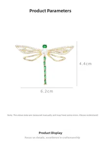 Detailed view of rhinestone dragonfly brooch with green gems and white pearl inlay