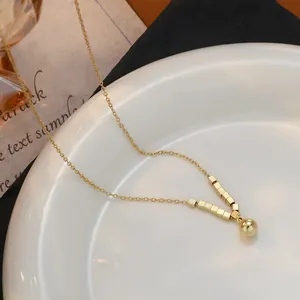 Detail van vergulde ketting met gepolijste vierkante kralen op een keramische rand