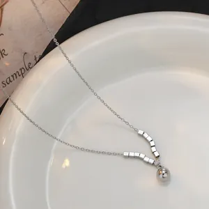 Macro-opname van zilveren V-vormige geometrische hanger ketting op wit porseleinen bord