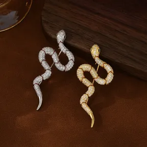 Macro detail of gold and silver snake brooches with pave zircon and green gem eyes