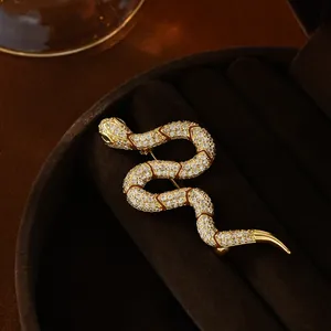 Macro shot of gold plated snake brooch with white zircons and green crystal eyes