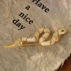 Detailed view of the gold serpent brooch featuring micro-set cubic zirconia and green eyes