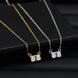 Detailed close-up of gold and silver necklaces with double zircon pendants on black box