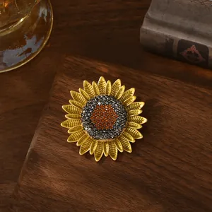 Elegant gold sunflower brooch with orange crystals on a vintage dark wood background