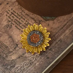 Vintage gold sunflower brooch with radiant petals and rhinestones on retro book