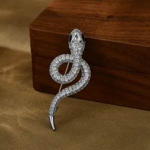 Silver snake-shaped brooch with white zircons and teardrop gemstone on dark wood display