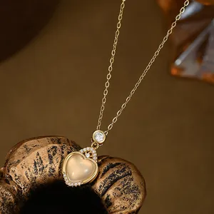 Detalle macro del colgante de corazón dorado con gema traslúcida y circonitas finas