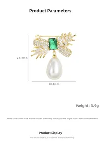Macro detail of elegant wheat brooch with green emerald, zircons and pearl drop charm