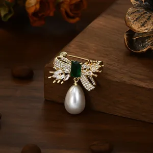 Elegant vintage gold bow brooch with emerald green stone and white drop pearl pendant
