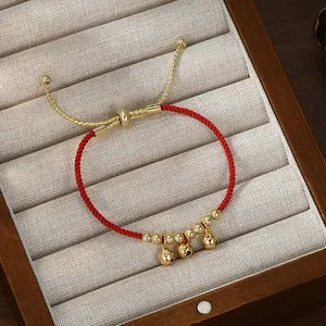 Bracciale a corda rossa intrecciata con tre campanelli dorati e chiusura a scorrimento