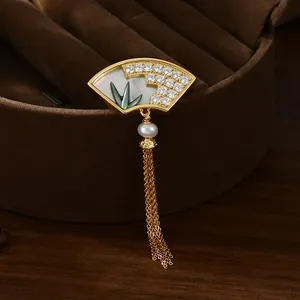 Détail de broche en forme d'éventail avec perle, nacre bambou et glands métalliques