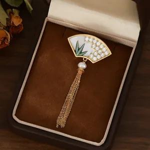 Détail de la broche en forme d'éventail avec motif bambou, perle et franges dorées