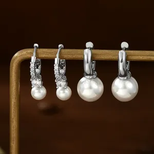 Detail of silver pearl earring set featuring pavé hoops and polished pearl drops