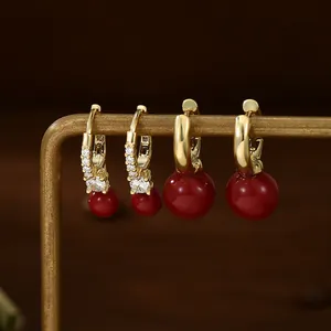Detail of vintage gold earrings set with micro-pave zircons and deep red pearls