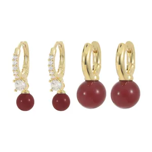Set of two gold-plated hoop earrings with deep red spherical pendants and crystal accents