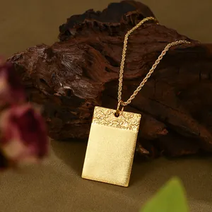Primer plano detallado de un colgante rectangular bañado en oro con relieve de olas