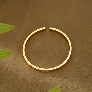 Dettaglio macro del bracciale rigido dorato opaco con motivi in rilievo stile vintage