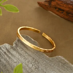 Dettaglio macro del bracciale aperto dorato con texture opaca e incisione in rilievo