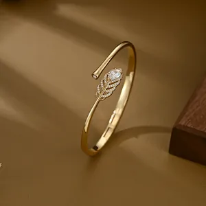 Elegant gold feather bangle with micro-pave cubic zirconia and pear-shaped stone