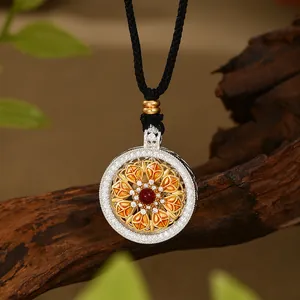 Detalle de collar de flor con gema roja y esmalte colorido sobre soporte de madera