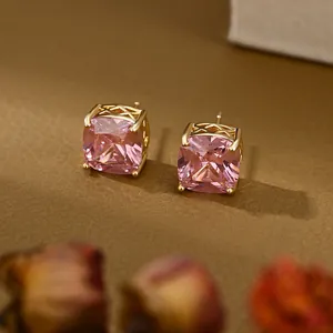Detail van roze vierkant geslepen edelsteen oorbellen met goudkleurige raster zetting