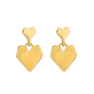 Detail of golden heart-shaped earrings with vertical brushed metal texture finish