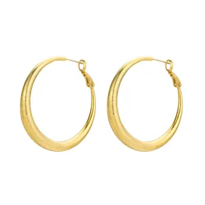 Close-up of golden teardrop hoop earrings with elegant sandblasted matte texture finish