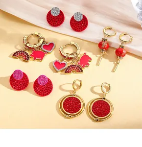 Vue à plat de boucles d'oreilles festives lanterne rouge et cœur avec accents dorés