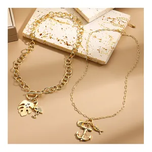 Detail of gold beach necklaces with flamingo, anchor, and shell pendants on stone surface