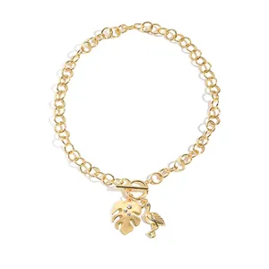 Golden ocean beach necklace with flamingo and monstera leaf charms and OT toggle clasp