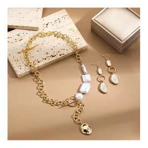 Dettaglio del set gioielli con perle barocche, catena dorata spessa e orecchini