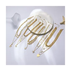 Detail of layered gold necklaces with heart and R letter pendants on a white plate