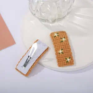 Détail de barrettes à fleurs en tricot fait main avec broderies blanches et jaunes