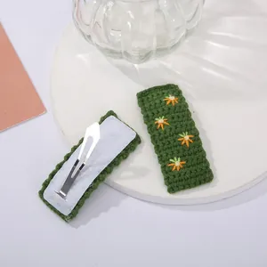 Détail de pinces à cheveux tricotées main vert foncé avec broderie florale et clip métal