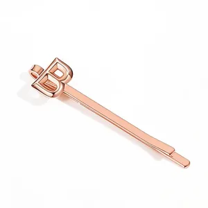 Detail view of the rose gold metal hair clip with a polished 3D architectural letter B