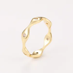 Detailed view of a gold wavy ring with sparkling white cubic zirconia stones