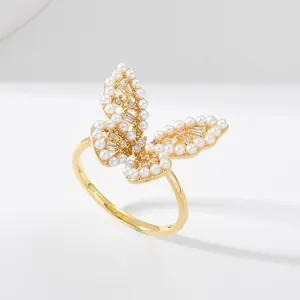 Detail of gold butterfly ring featuring inlaid white pearls and sparkling zircons