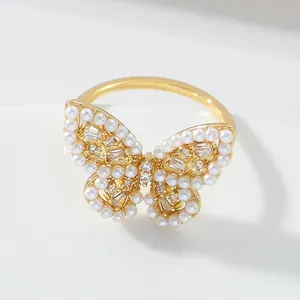 Elegant gold butterfly ring with inlaid pearls and zircon stones on white background