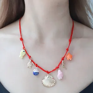 Red cord necklace with mixed sea charms including golden shell and colorful pendants